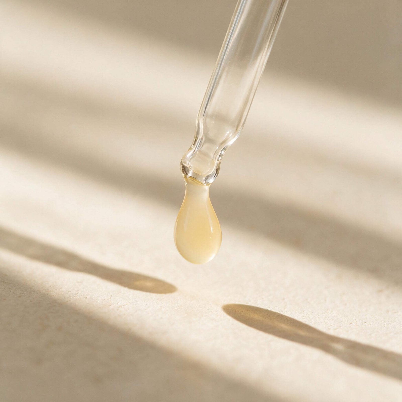 Close-up of a glass dropper releasing a serum droplet